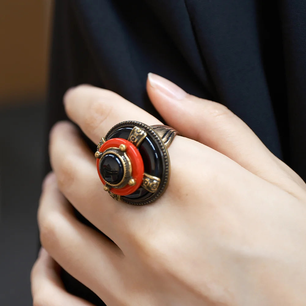Bague Agate "Merveille d'Antan" avec une pierre d'agate noire centrale, entourée d'un anneau rouge corail et d'une monture en métal vieilli complexe.