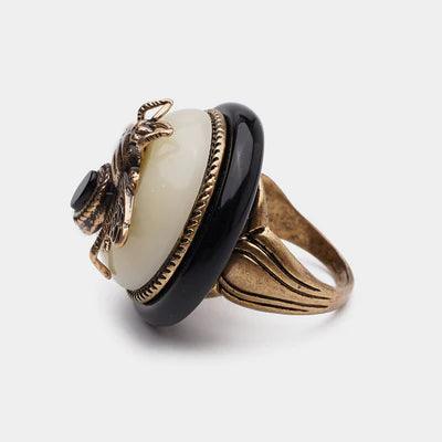Bague "Reine Noire" avec une pierre d'agate noire, un cabochon blanc nacré et un scarabée doré détaillé sur le dessus.