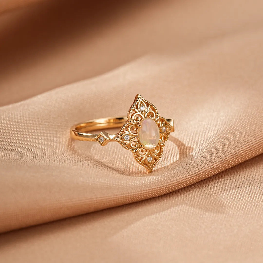 Bague en argent doré or 10K avec une opale ovale et des détails filigranes, ornée de petits diamants sur les côtés.