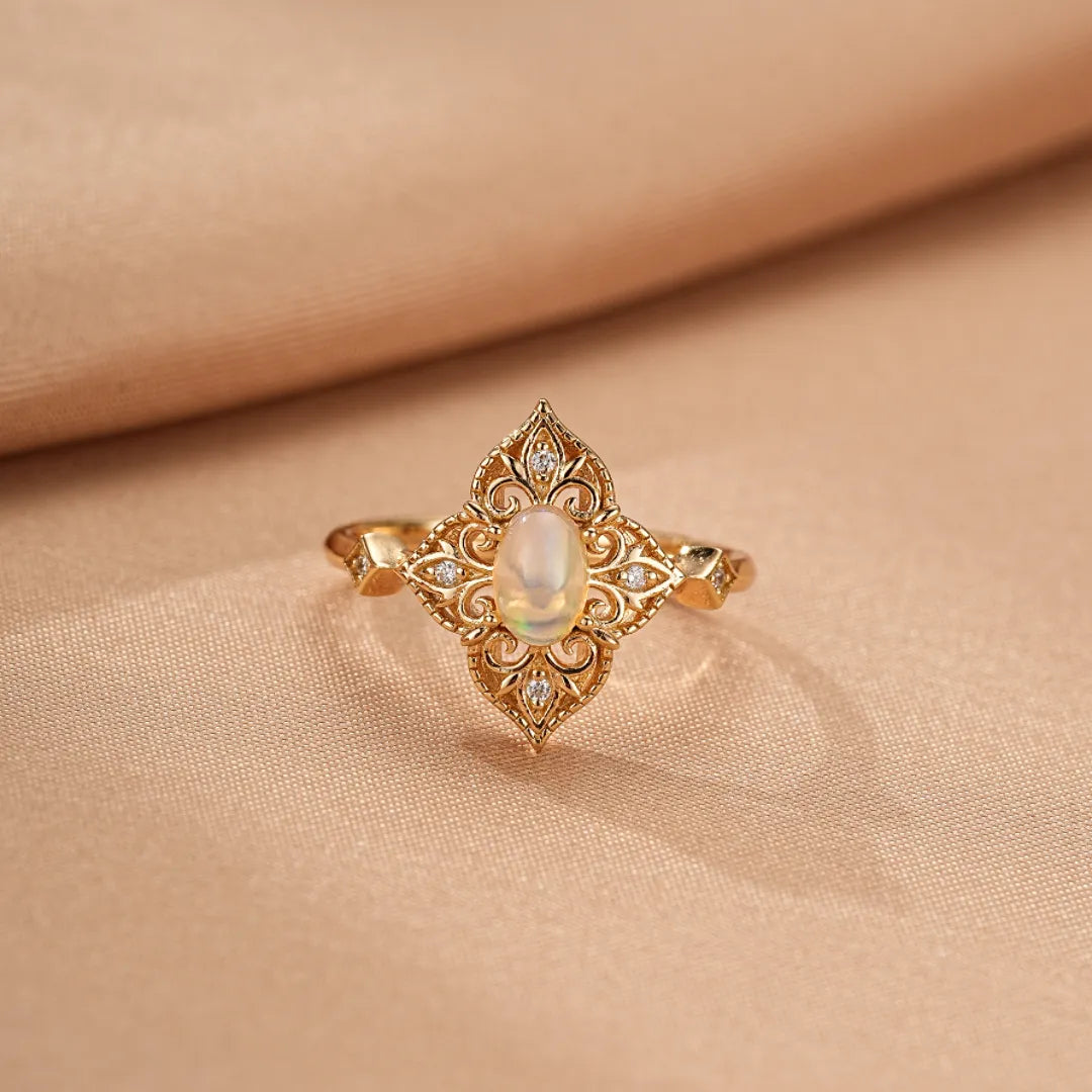 Bague en argent doré or 10K avec une opale ovale centrale et de petites pierres serties dans un design complexe de style antique.