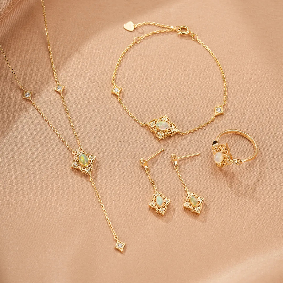 Ensemble de bijoux en argent doré 10K avec des opales blanches et des diamants, comprenant une bague, un bracelet, un collier et des boucles d'oreilles.
