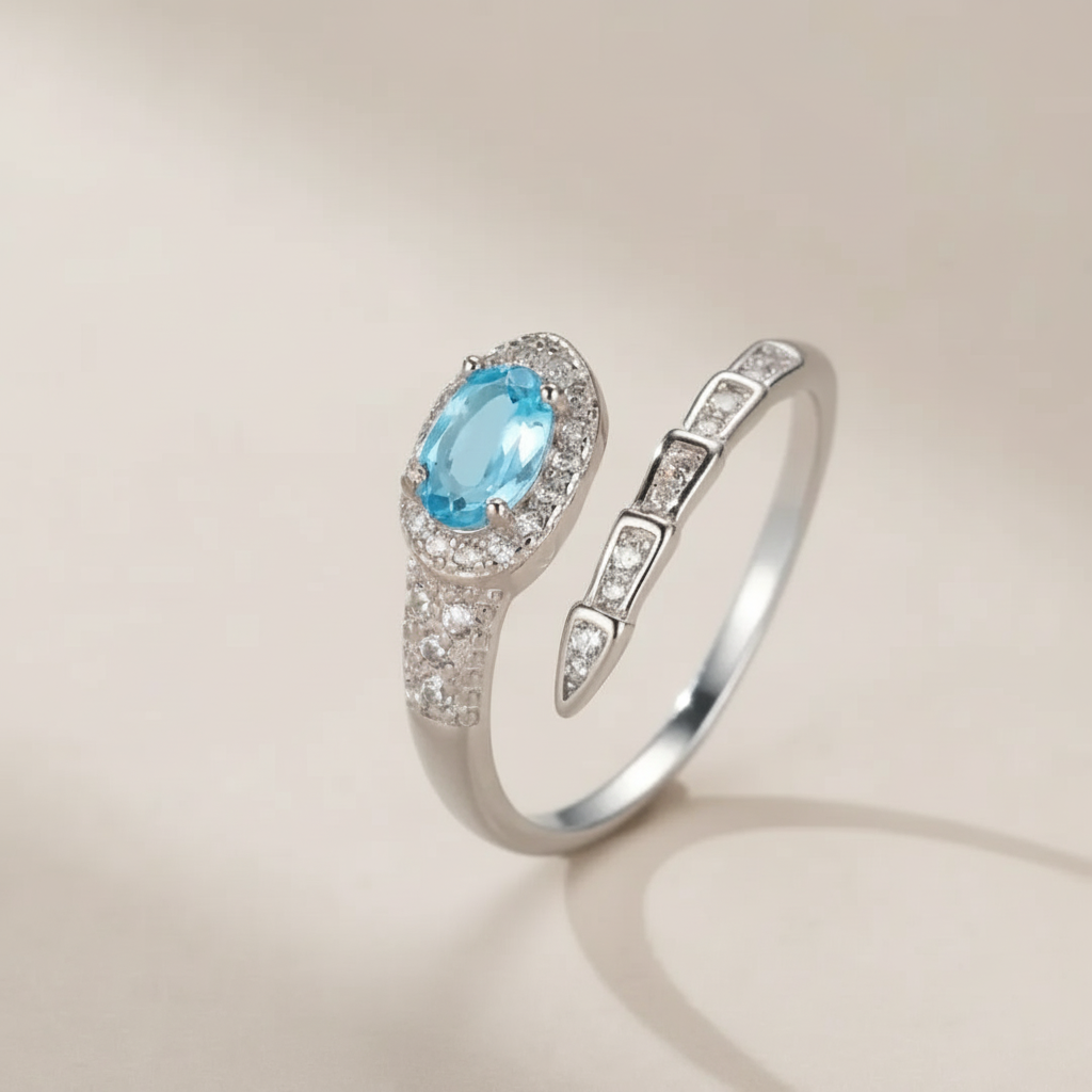 Bague serpent en argent 925 ornée d'une topaze bleue ovale sertie de petits cristaux, design ouvert.