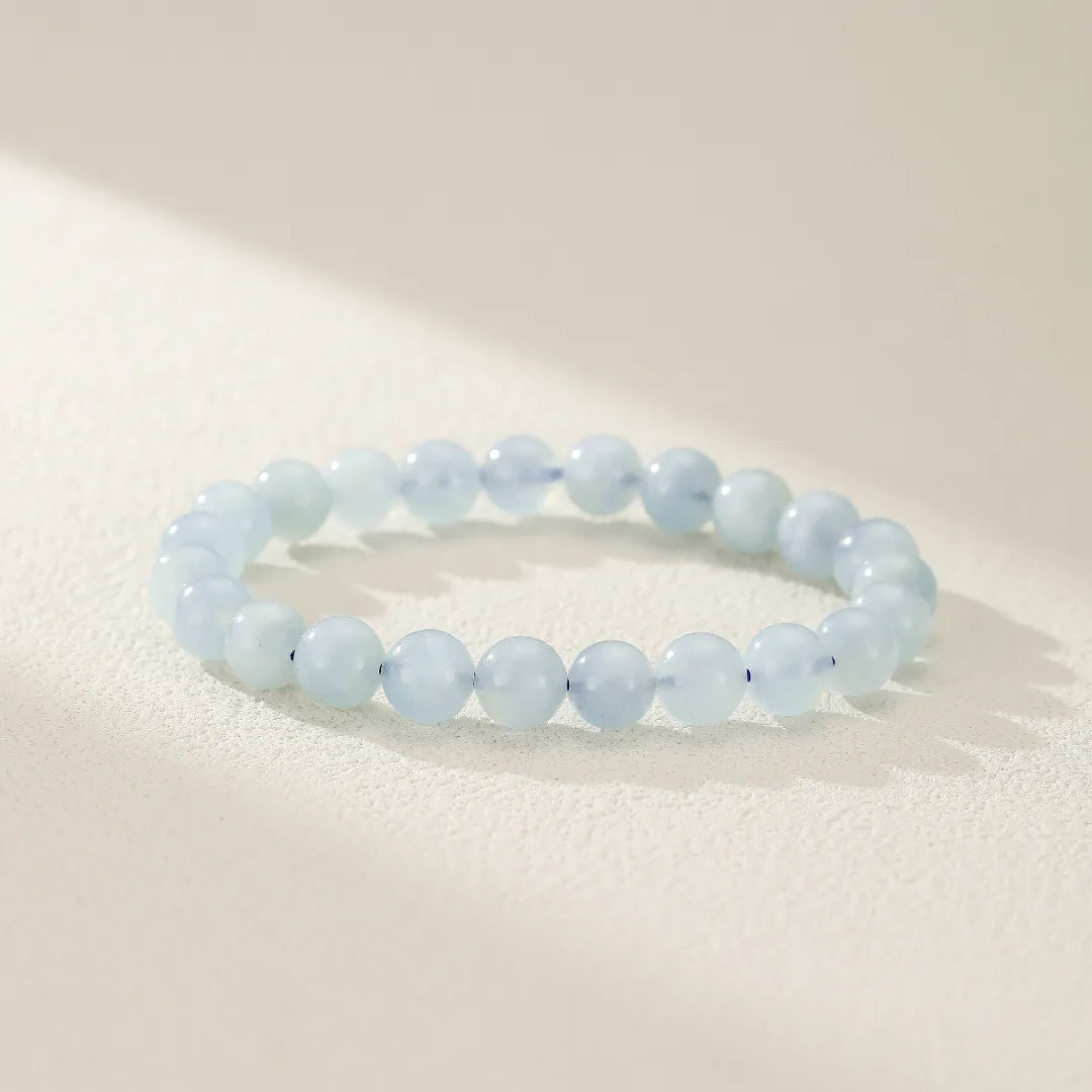 Bracelet "Douceur Calmante" en aigue-marine, composé de perles rondes bleu pâle, sur un fond clair avec des ombres douces.