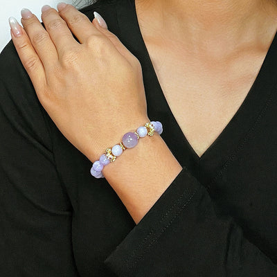 Bracelet élastique avec des perles d'améthyste, de calcédoine et des éléments dorés, porté au poignet d'une femme.