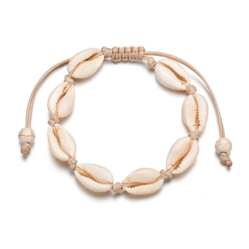Bracelet de cheville en coquillages cauris naturels sur cordon beige réglable, style bohème chic.