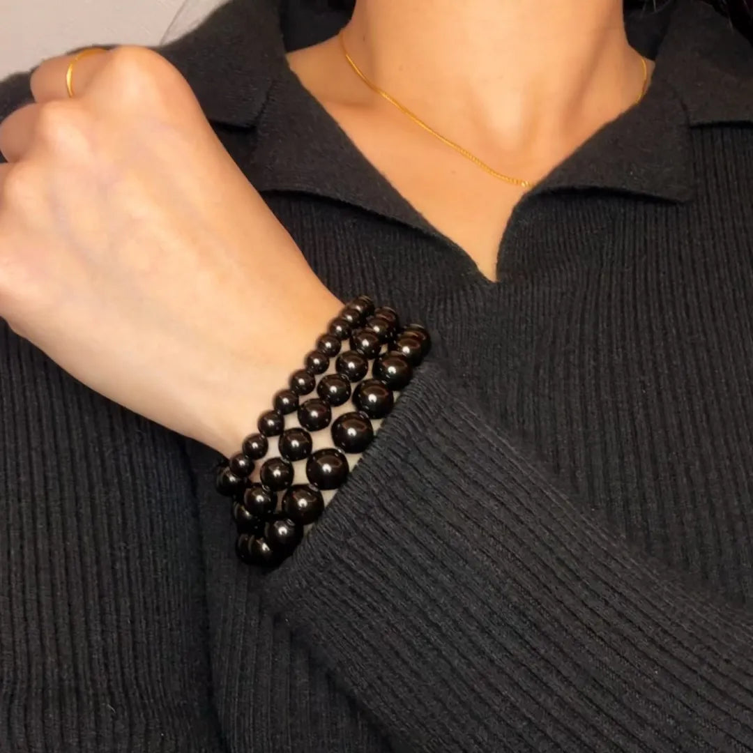 Bracelet triple rangs en perles d'obsidienne naturelle, porté au poignet d'une femme.
