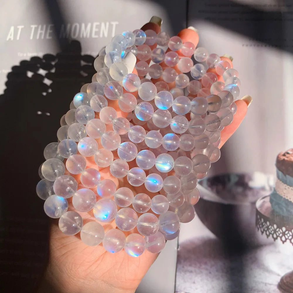 Ensemble de bracelets en pierre de lune naturelle "Rêve Doux" aux reflets bleus et rosés, tenus dans une main.