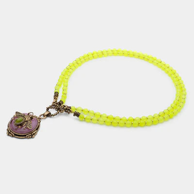 Collier avec pendentif "Abeille d'Or" en agate jaune, ornements en bronze et pierre verte, sur fond blanc.