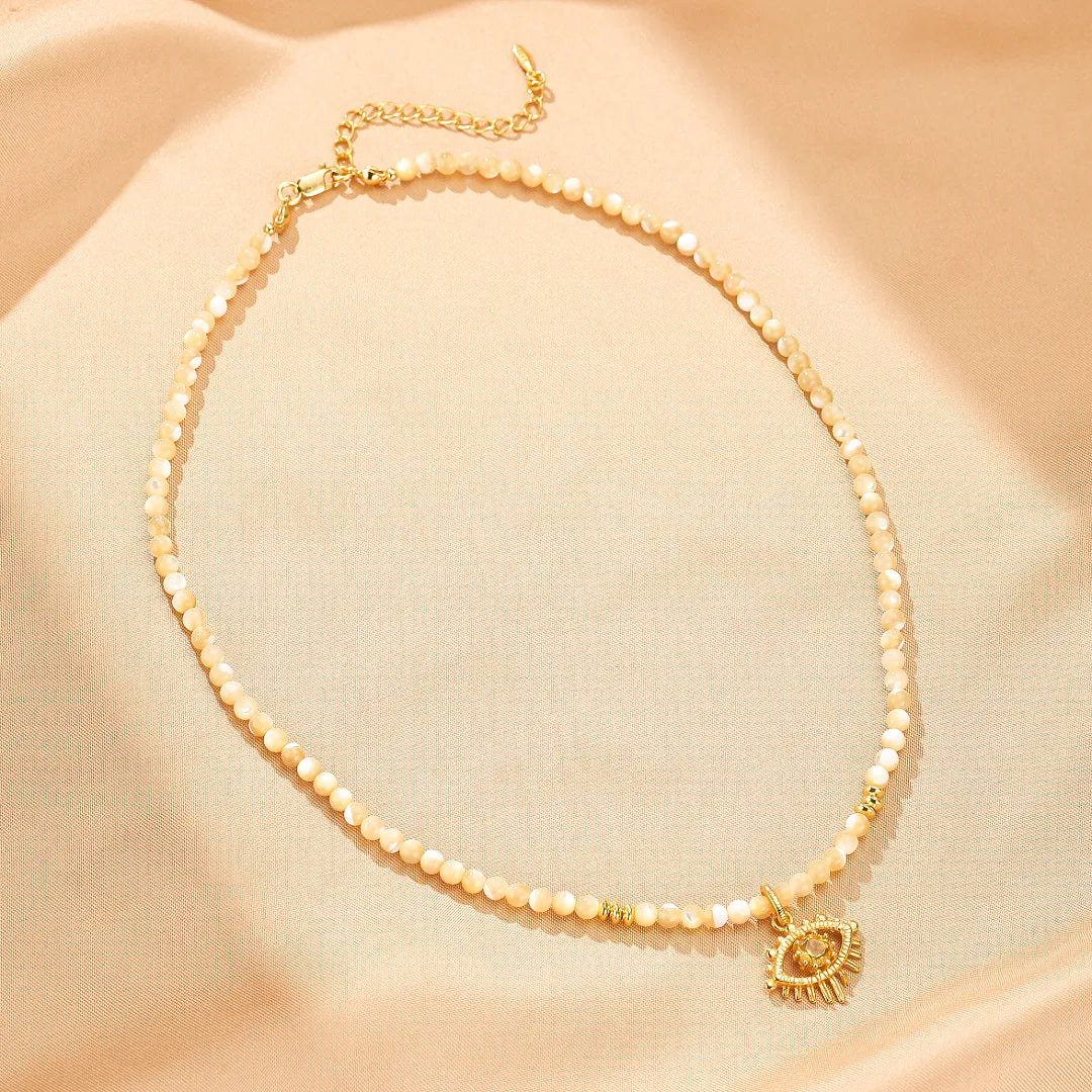 Collier "Regard Protecteur" en argent doré or, orné de perles fines couleur ivoire et d'un pendentif œil stylisé serti d'une citrine dorée.