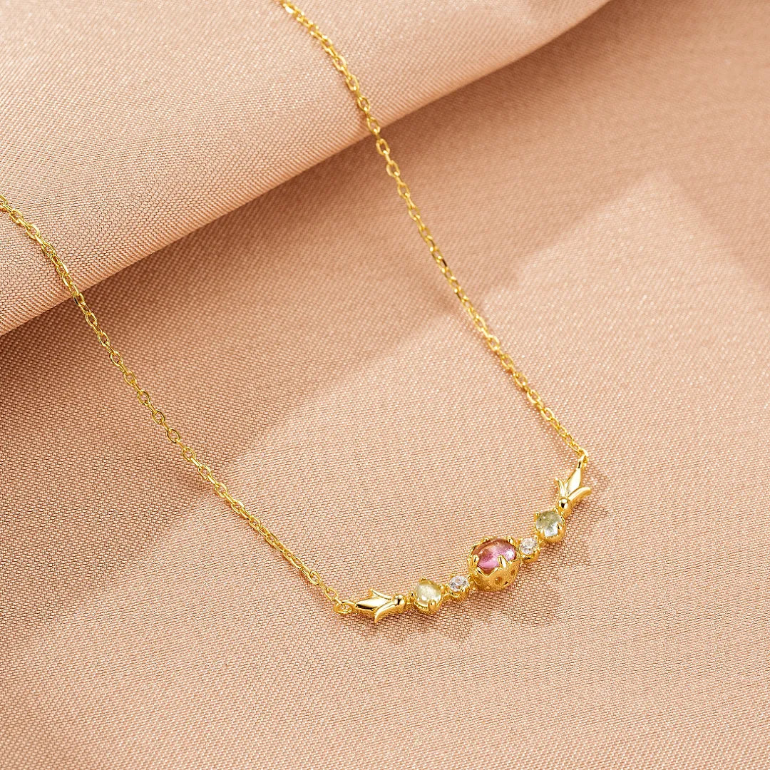 Collier "Douceur Éclatante" en Argent Doré Or 18K, orné d'une tourmaline rose centrale, de topazes bleues, de péridots verts et de zircons blancs, le tout monté sur une fine chaîne dorée.