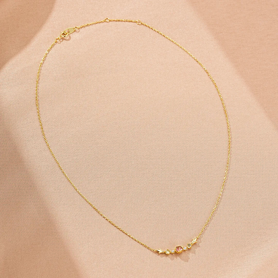 Collier fin en argent doré or 18K, orné de petites pierres colorées dont une tourmaline rose, une topaze bleue et un péridot vert, formant un motif étincelant.