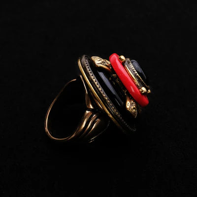 Bague "Merveille d'Antan" en métal doré vieilli avec une pierre d'agate noire, des accents rouges et des détails serpentins.