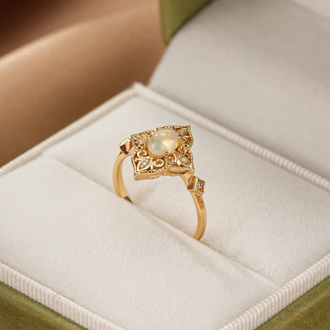 Bague en argent doré or 10K avec une opale centrale et des détails floraux gravés, sertie de petits diamants.