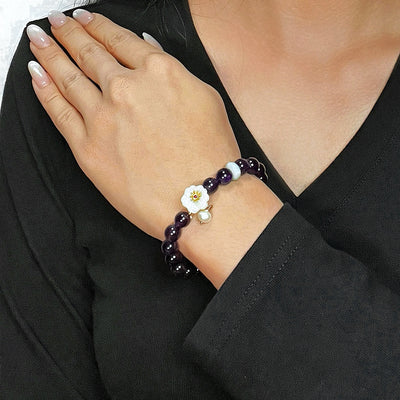 Bracelet "Fleur d'Harmonie" en améthyste, jade et perle, porté au poignet d'une femme.