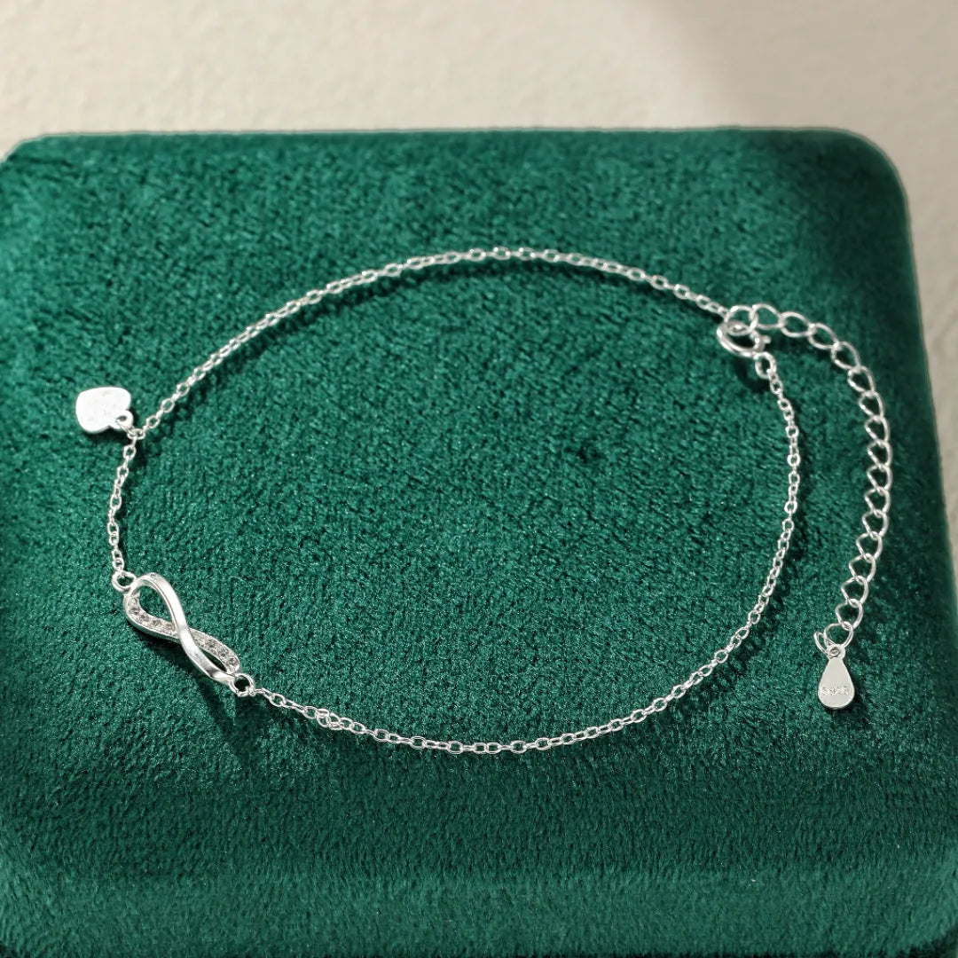 Bracelet de cheville en argent 925 avec un motif infini serti de zircons et un petit cœur suspendu.