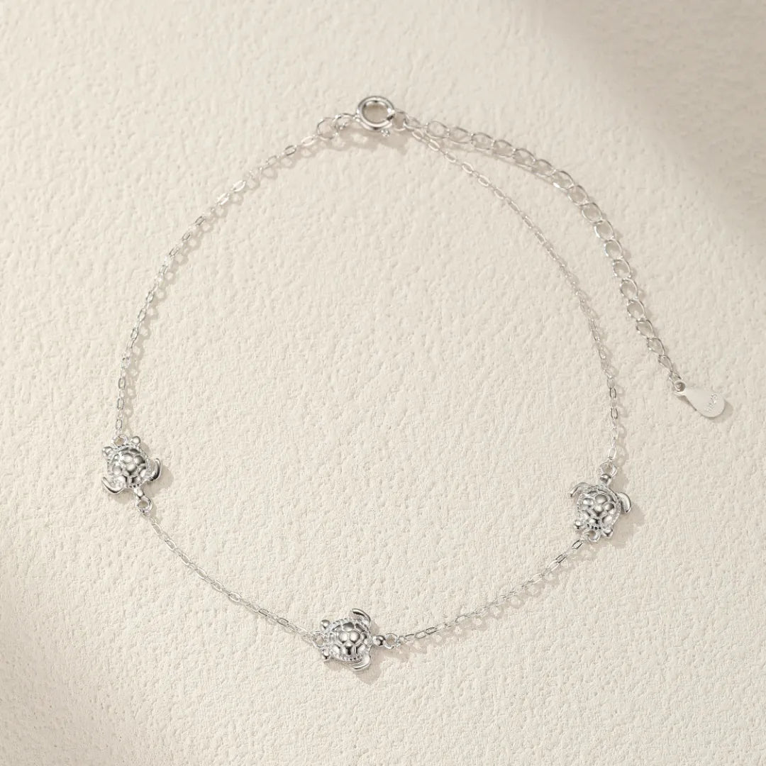 Bracelet de cheville en argent 925 avec trois petites tortues serties de zircons cubiques, chaîne fine et ajustable.