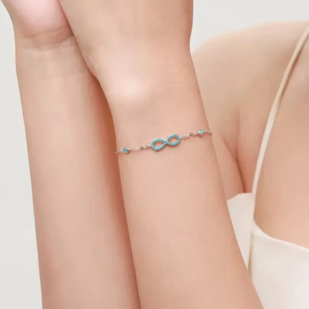 Bracelet Infini Turquoise "Souffle d'Infini" en argent 925, montrant le symbole de l'infini orné de petites pierres bleues turquoise sur un poignet.