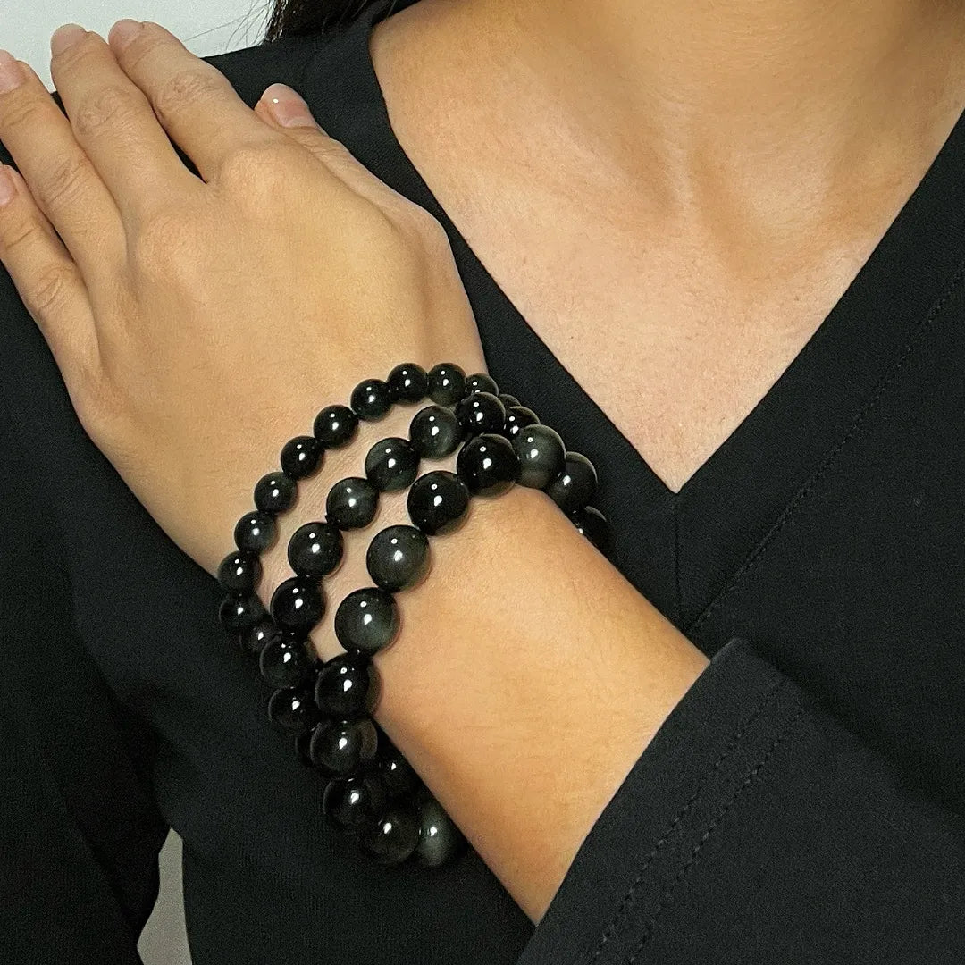 Bracelet fait de perles d'obsidienne arc-en-ciel sur le poignet d'une femme.
