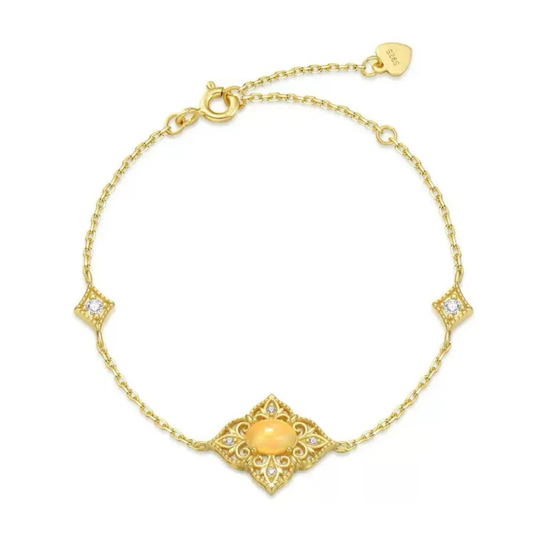 Bracelet chaîne en argent doré à l'or 10K avec une opale jaune ovale centrale sertie dans un pendentif ajouré orné de petits diamants et de motifs floraux. Deux petits pendentifs carrés avec un diamant sont placés symétriquement sur la chaîne.