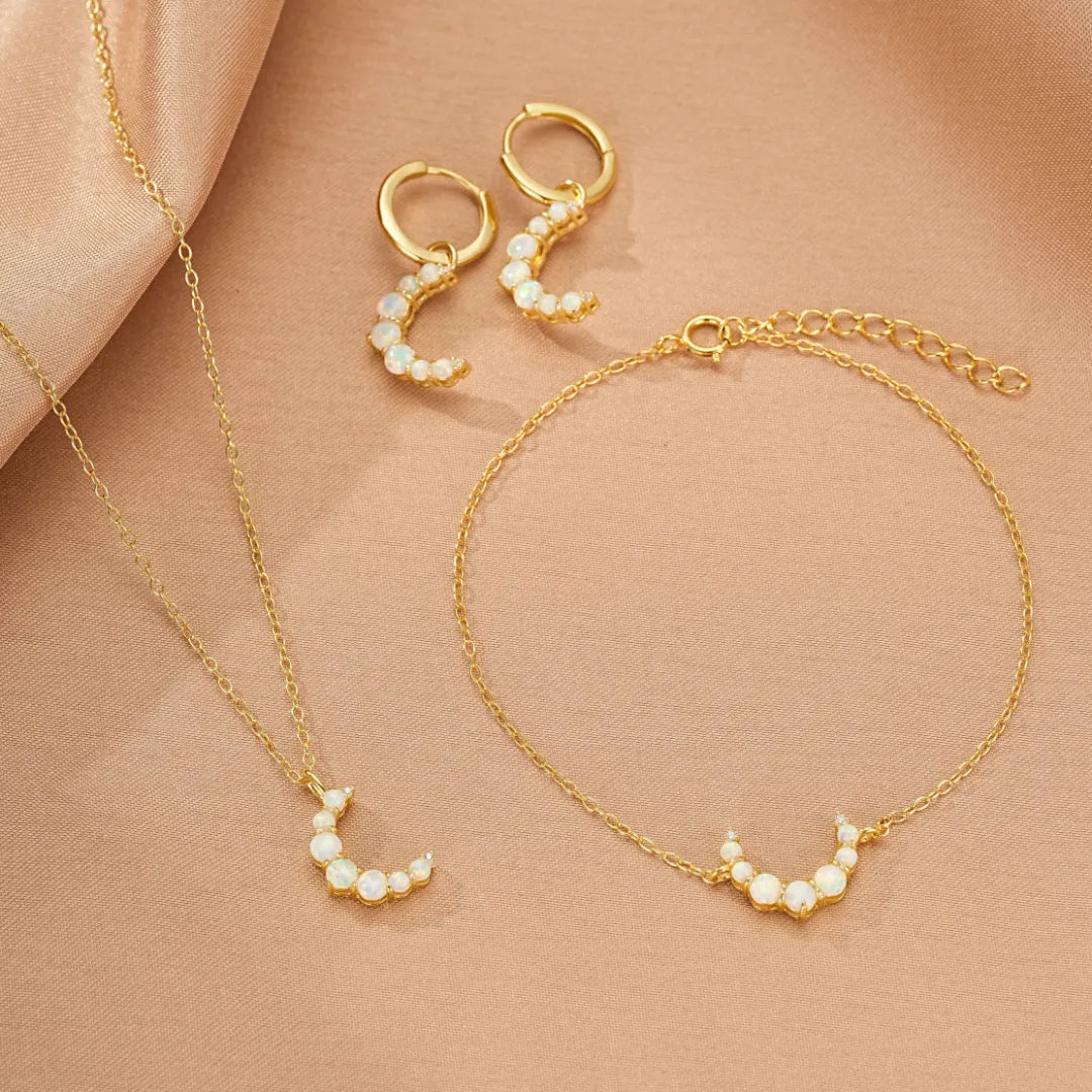 Ensemble de bijoux en argent doré 18 carats "Lune Douce" comprenant un bracelet, une paire de boucles d'oreilles créoles et un collier, tous ornés d'opales formant un croissant de lune.