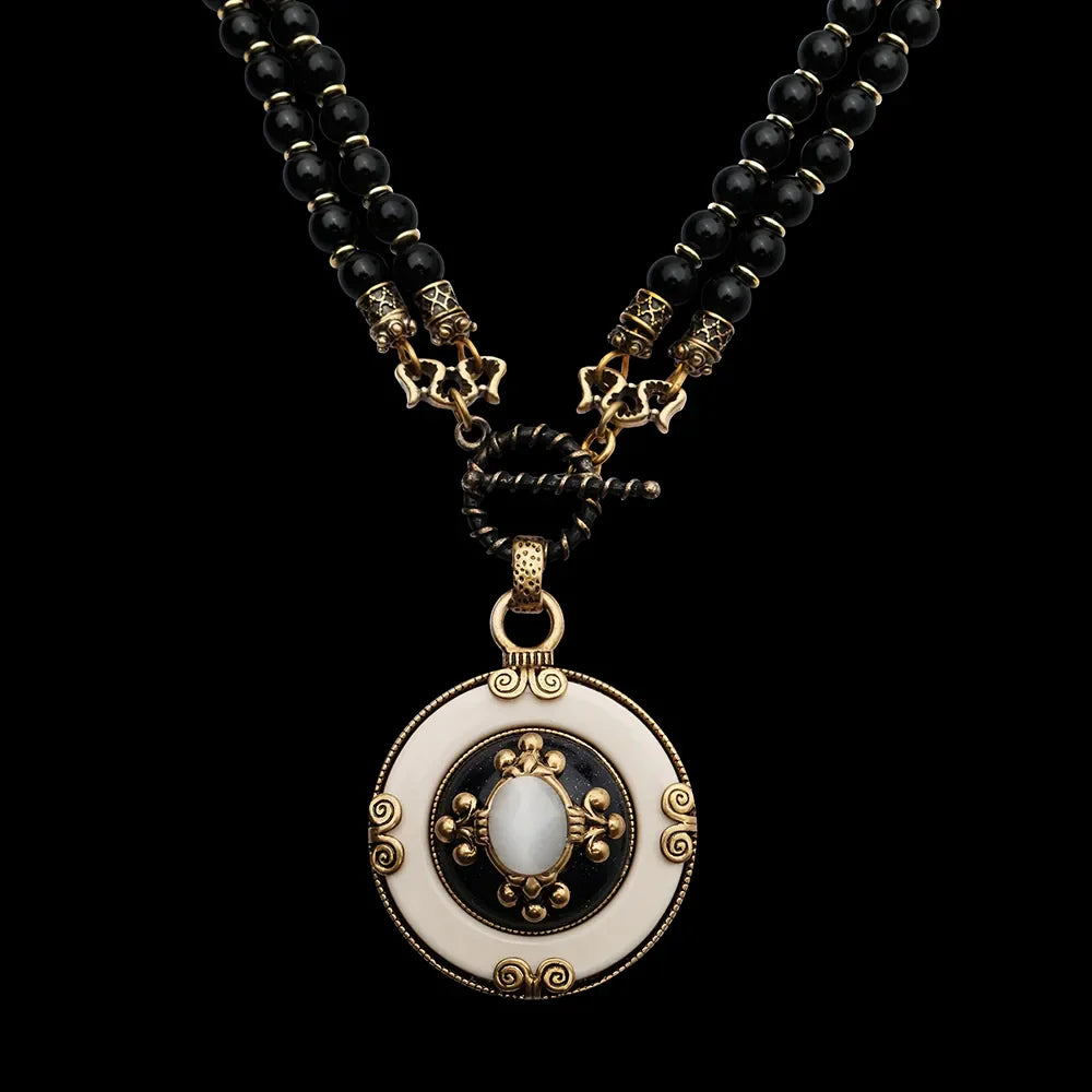 Collier double rang en perles d'agate noire avec un pendentif rond orné d'une pierre blanche ovale et de détails dorés