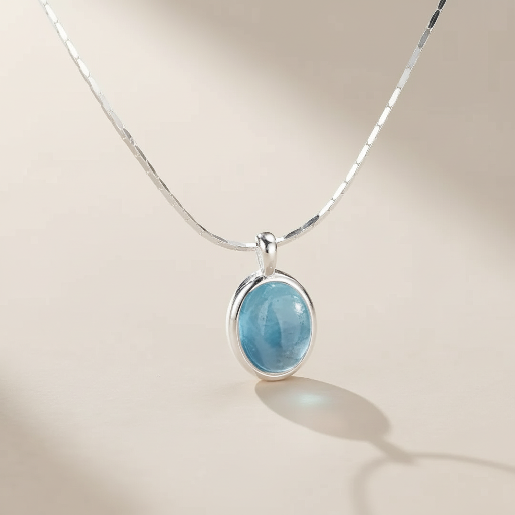 Collier en argent avec un pendentif ovale en aigue-marine bleu clair, chaîne serpent fine.