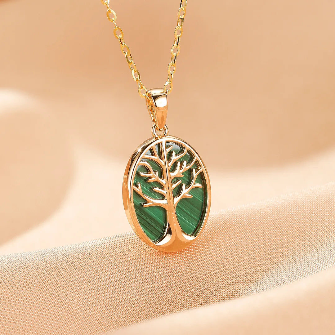 Pendentif ovale en argent doré représentant un arbre de vie stylisé avec une incrustation de malachite verte, suspendu à une chaîne dorée.