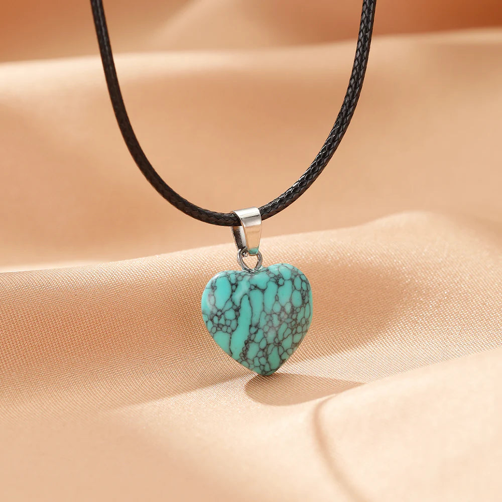 Collier avec pendentif en forme de cœur en turquoise brute, sur un cordon noir.