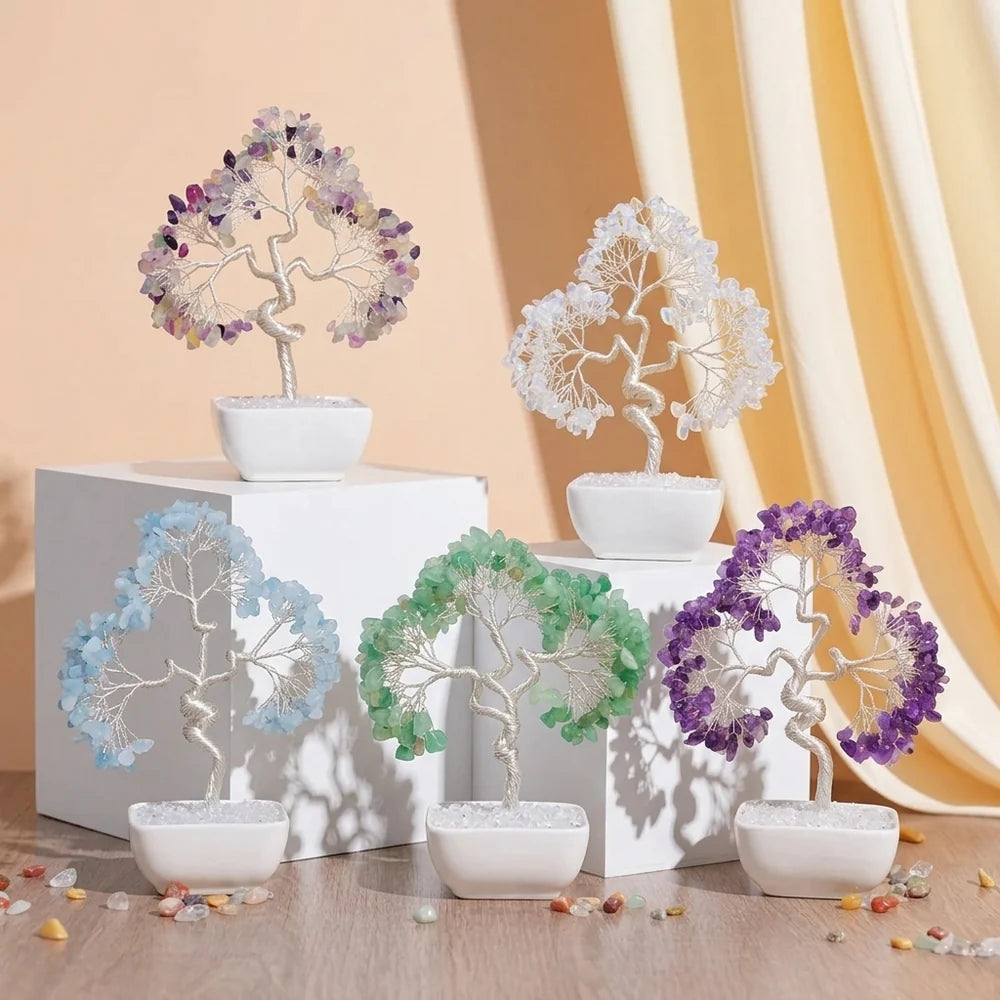 Cinq arbres de vie décoratifs en pierres naturelles colorées (améthyste, quartz blanc, quartz bleu, aventurine verte, améthyste) avec des troncs en fil argenté, posés sur des socles blancs.