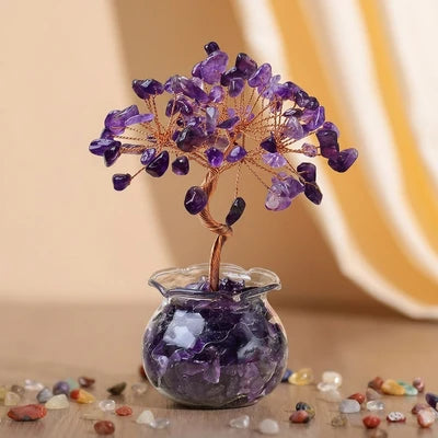 Arbre de Vie décoratif en pierres d'améthyste violettes, avec un tronc et des branches en fil de cuivre, reposant dans un pot en verre rempli de cristaux d'améthyste.